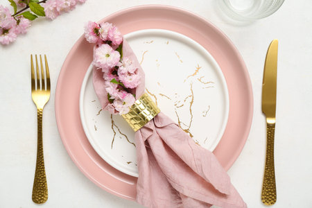 Beautiful table serving with cutlery, blooming tree branches and folded napkin on white background