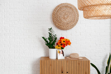 Vase with beautiful tulip flowers and houseplant on wooden cabinet in interior of living roomの写真素材