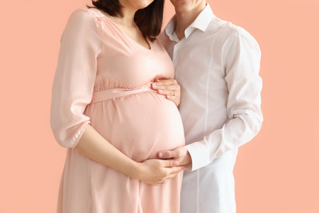Young pregnant couple on pink background, closeupの写真素材