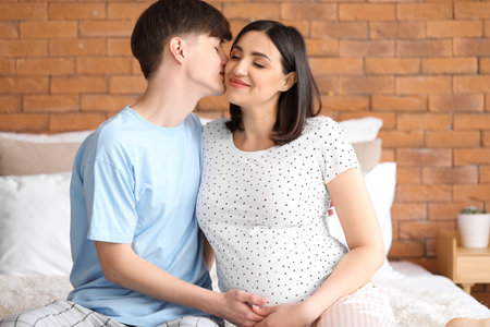 Young pregnant couple sitting in bedroomの写真素材