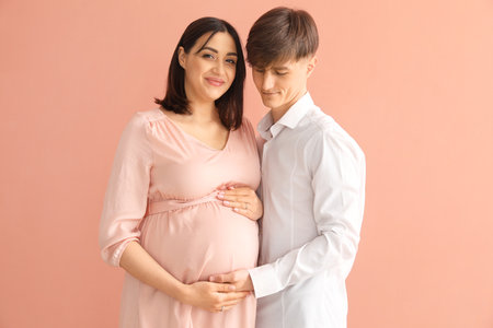 young pregnant couple on pink backgroundの写真素材