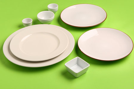 Composition with clean plates and bowls on green backgroundの写真素材