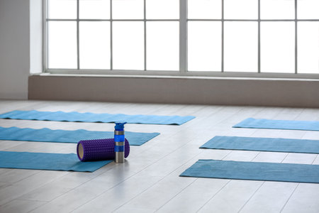 Bottle of water with foam roller and yoga mats in gymの写真素材
