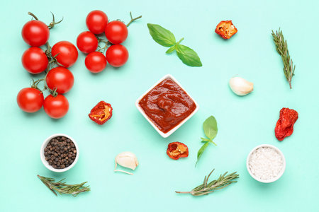 Bowl of delicious tomato sauce and ingredients on turquoise backgroundの写真素材