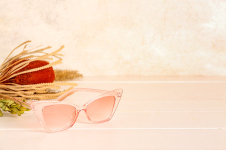 Stylish sunglasses with dried flowers on white wooden table, closeupの写真素材