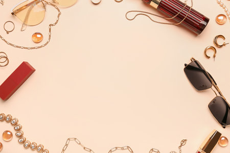 Frame made of sunglasses, jewelry and lipsticks on beige backgroundの写真素材