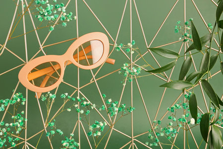 Stand with sunglasses, flowers and plant branches on green backgroundの写真素材