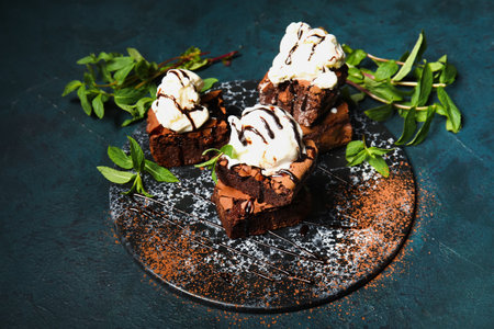 Board with pieces of tasty chocolate brownie and ice cream on dark backgroundの写真素材