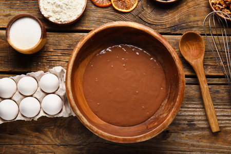 Bowl with dough and ingredients for preparing chocolate brownie on wooden backgroundの写真素材