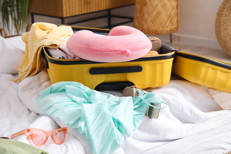 Open suitcase with beach accessories on bed in roomの写真素材