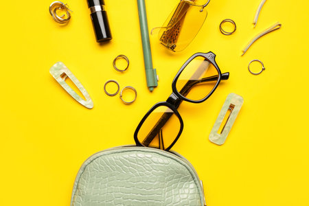 Cosmetic bag with sunglasses and accessories on yellow backgroundの写真素材