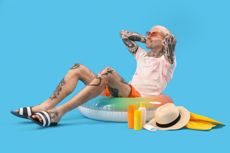 Tattooed man with beach accessories on light blue backgroundの写真素材