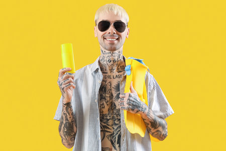 Tattooed man with paddles and sunscreen cream on yellow backgroundの写真素材