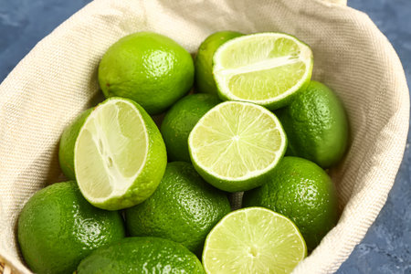 Wicker bowl with fresh limes on blue backgroundの写真素材
