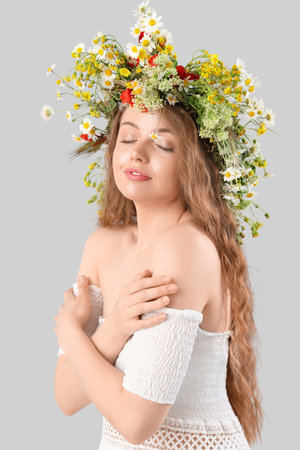 Beautiful young woman in flower wreath on light background. summer solsticeの写真素材