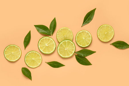 Slices of fresh lime with leaves on orange background