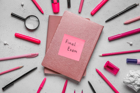 Frame made of different stationery and notebooks with text FINAL EXAM on grunge white background
