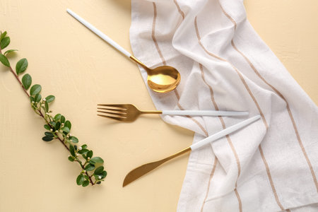 Golden cutlery with kitchen towel and cotoneaster twig on yellow backgroundの写真素材