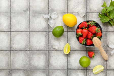 Bowl with ripe strawberry, lime, lemon and mint on tile backgroundの写真素材