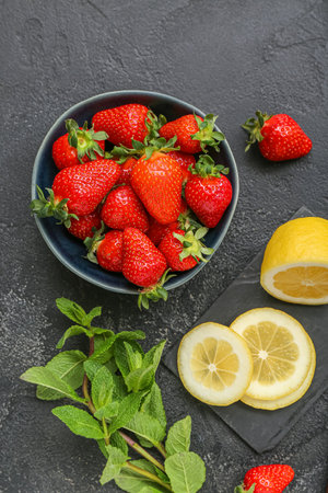 Bowl with ripe strawberry, lemon and mint on dark backgroundの写真素材