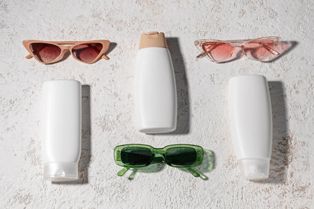 Bottles of sunscreen cream and different sunglasses on grunge white backgroundの写真素材