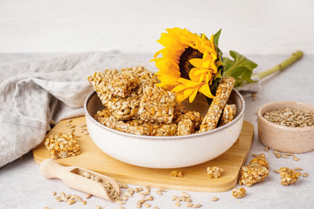 Board with bowls of tasty kozinaki, sunflower and seeds on white backgroundの写真素材