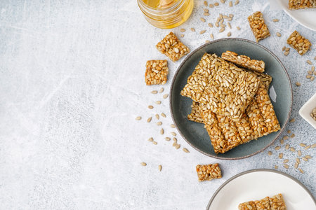 Plates with tasty kozinaki, sunflower seeds and jar of honey on white grunge backgroundの写真素材