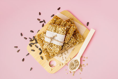 Board with tasty kozinaki and sunflower seeds on pink backgroundの写真素材