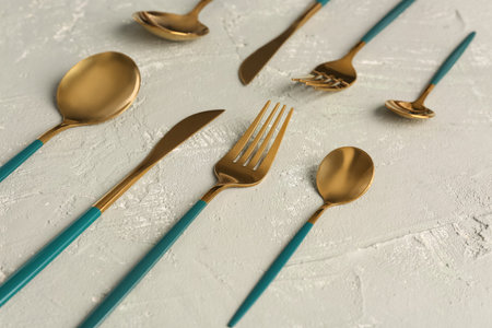Golden set of cutlery with green handles on gray backgroundの写真素材