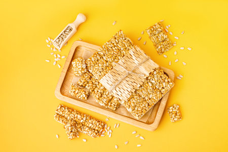 Board with tasty kozinaki and sunflower seeds on orange backgroundの写真素材