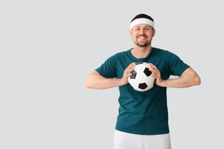 Happy man with soccer ball on light backgroundの写真素材