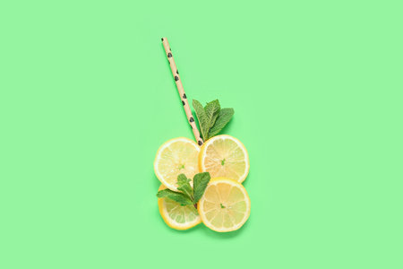 Slices of ripe lemon with mint and straws on green backgroundの写真素材