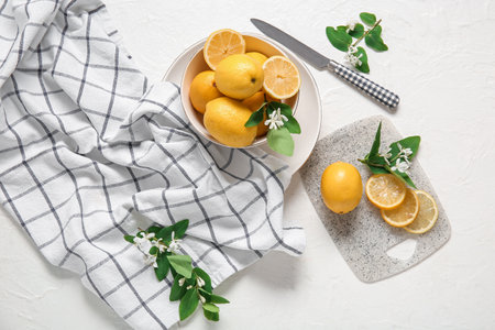 Bowl and board of lemons with blooming branches on white tableの写真素材