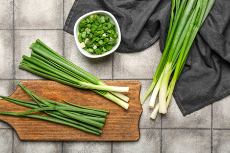 Wooden board and bowl with fresh green onion on dark tile backgroundの写真素材