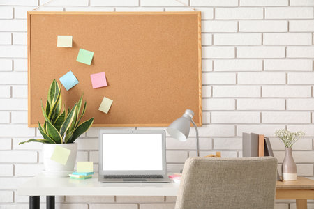 Board with sticky notes and laptop on table in roomの写真素材
