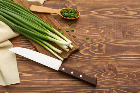 Board with fresh green onion on wooden backgroundの写真素材