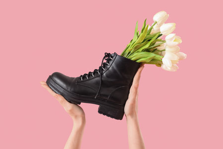 Female hands with tulip flowers in shoes on pink backgroundの写真素材
