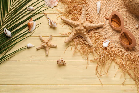 Composition with stylish hat, sunglasses, starfishes, seashells and palm leaf on color wooden...