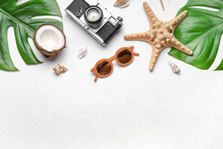 Composition with stylish sunglasses, photo camera, palm leaves, coconut and seashells on light...