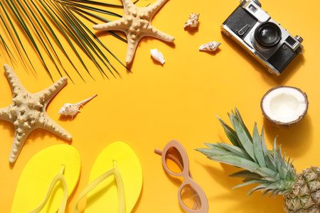Frame made of beach accessories, fruits, photo camera and starfishes on color backgroundの写真素材