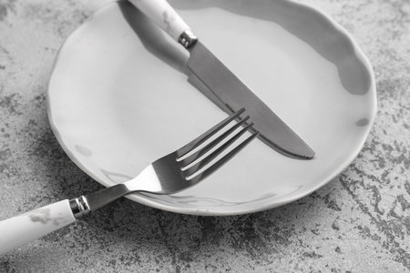 Silver fork with knife and plate on gray grunge tableの写真素材