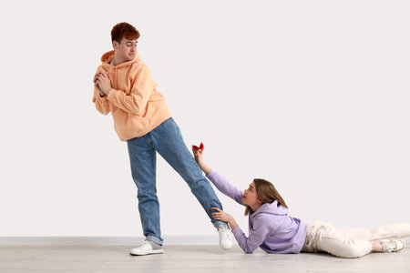 Young woman begging her boyfriend to marry her near light wallの写真素材
