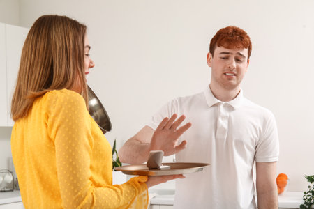Young man rejecting marriage proposal from her girlfriend in kitchenの写真素材