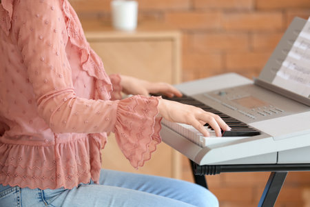 Young female musician playing synthesizer at homeの写真素材