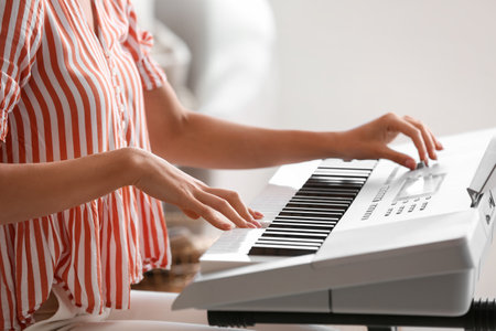 Young female musician playing synthesizer at homeの写真素材