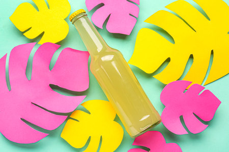 Composition with bottle of fresh soda and paper leaves on turquoise backgroundの写真素材
