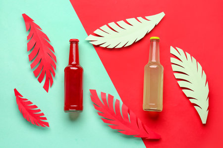 Composition with bottles of fresh soda and paper leaves on color backgroundの写真素材