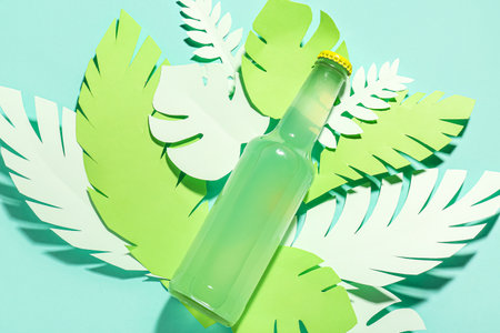 Composition with bottle of fresh soda and paper leaves on turquoise backgroundの写真素材