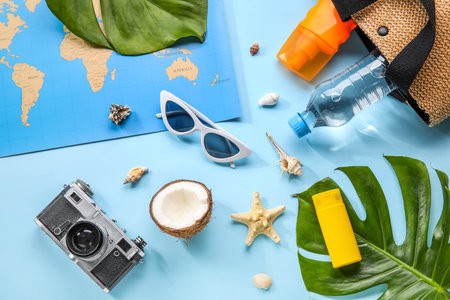 Composition with world map, bottle of sunscreen cream, sunglasses, coconut and seashells on blue backgroundの写真素材