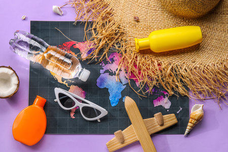 Composition with world map, bottle of sunscreen cream, sunglasses and wooden plane on purple backgroundの写真素材